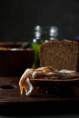 Geleneksel Rus çorbası, tütsülenmiş domuz pastırması ve rustik arka planda çavdar ekmeği.