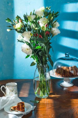 Mavi duvarda bir buket taze çiçek.