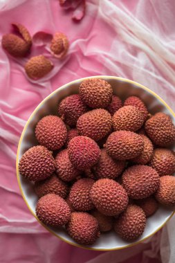 Pembe arka planda bir kasedeki liçi meyvelerinin yukarıdan görünüşü