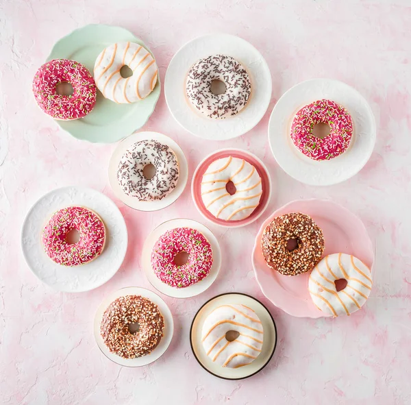 Assorted glazed doughnuts on a pink background