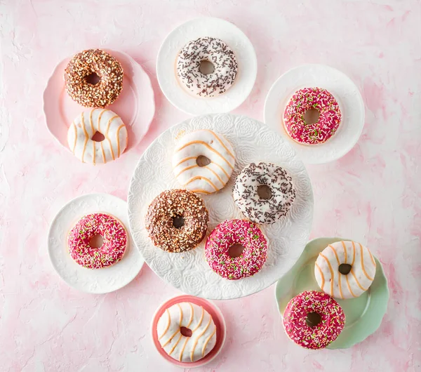 Assorted glazed doughnuts on a pink background