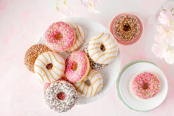 Assorted glazed doughnuts on a pink background