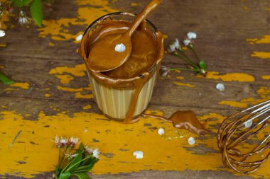 Sarı bahçe masasında servis edilen bir bardakta Kore dalgona kahvesi yapmak, üzerinde krema dolu kaşık, yakın görüş. Yatay yönelim