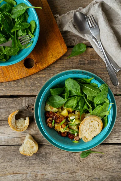 Ensalada de patatas, tocino y salchichas con espinacas frescas, al estilo rústico — Foto de Stock