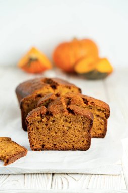 Beyaz ahşap arka planda yarım dilimlenmiş balkabağı ekmekli kek. Portre yönelimi