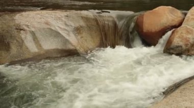 Yüksek çözünürlüklü büyük çakıl, kayalar ve bambu Köprüsü basamaklı beyaz su acele ile eylem engebeli dağ nehir şelaleler panoramik sahne, kaydırma. Stok görüntüleri Hd video klip.