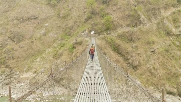 当地男子在尼泊尔河上行走吊桥。马纳斯卢峰电路跋涉. — 图库视频影像