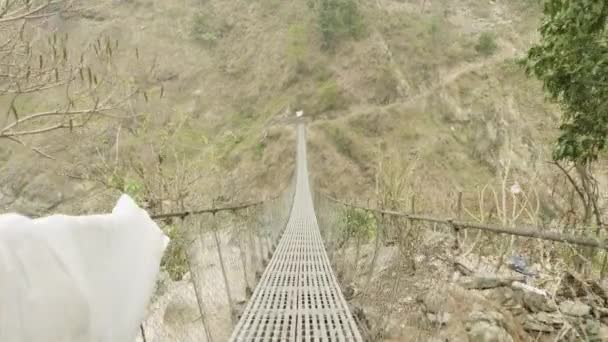 Hängbron över floden i bergen i Nepal. Manaslu circuit trek. — Stockvideo