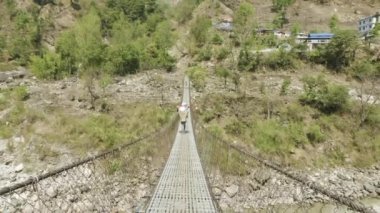 Yerel erkekler Nehri Nepal asma köprü üzerinde ağır bir yük taşıyor.