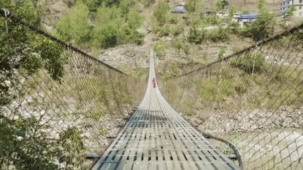 Des enfants locaux courent et jouent sur le pont suspendu sur la rivière au Népal . — Video