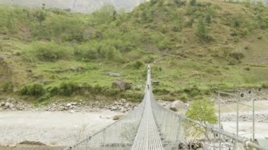 Backpackers Nepal Nehri üzerinde asma köprü üzerinde yürümek. Manaslu devre trek.