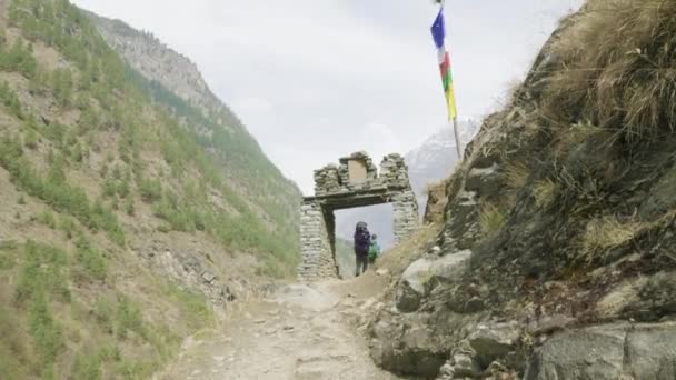 Backpackers lopen door de poort op nepalese pad rond de berg Manaslu. — Stockvideo