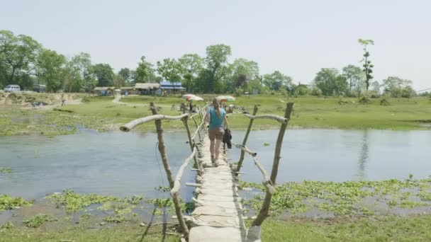 Ragazza cammina lungo il ponte di legno attraverso il fiume, Asia, Nepal . — Video Stock