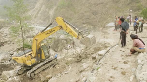 MANASLU, NEPAL - MARCH, 2018: Excavator repairs a stone road in the mountains. — Stock Video