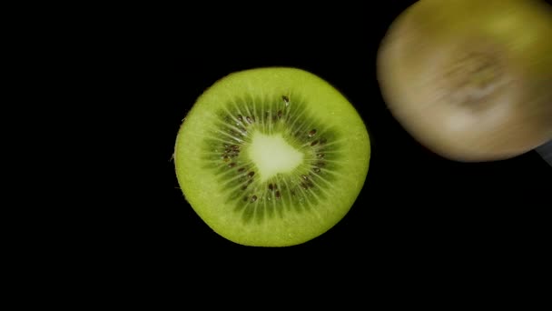 Kiwi verde aislado cortado con un cuchillo en el estudio sobre un fondo negro — Vídeos de Stock