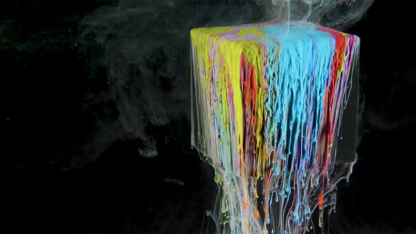 Многоцветная чернильная краска медленно течет из куба под водой — стоковое видео