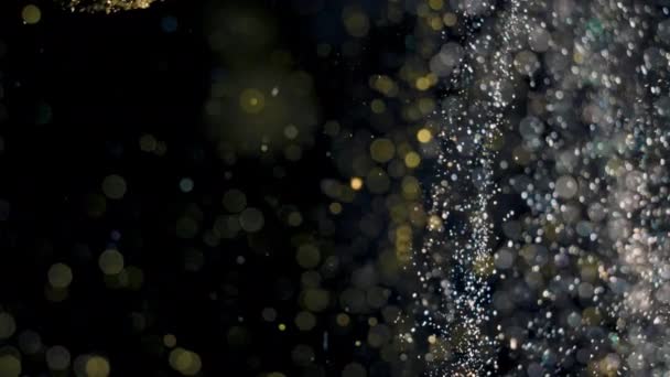 Eleganckie, szczegółowe i złote cząstki płyną z płytką głębią pola pod wodą — Wideo stockowe