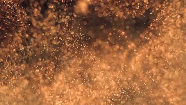 Elegante, detaillierte und goldene Teilchen fließen mit geringer Schärfentiefe unter Wasser — Stockvideo
