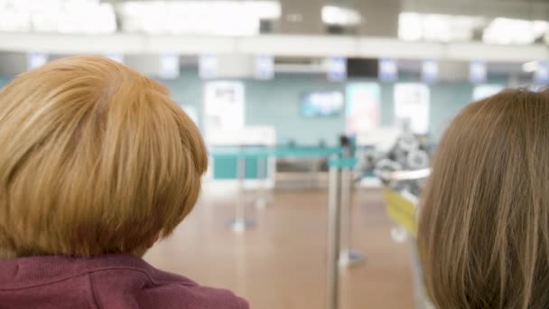 Dos mujeres caucásicas felices hablando en el aeropuerto y esperando el vuelo — Vídeo de stock