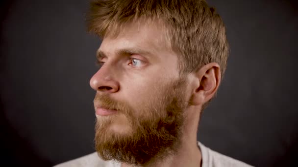 Fél szakállas férfi elforgatja az arcát a sötét izolált stúdióban — Stock videók