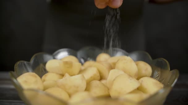 Чоловік солона картопля на темній кухні — стокове відео