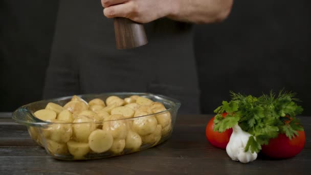 Человек перцовый картофель из перечного горшка на темной кухне — стоковое видео