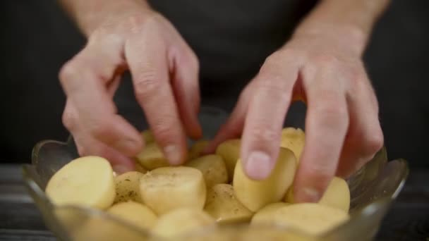 Férfi mixex burgonya fűszerek és olívaolaj tálban a sötét konyhában — Stock videók