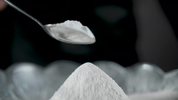 Koch streut Mehl mit Salz auf schwarzem Hintergrund — Stockvideo
