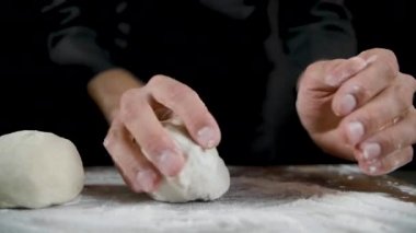 Şef koyu bir arka plan üzerinde hamur çörekler yapar