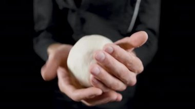 Şef koyu bir arka plan üzerinde hamur çörekler yapar