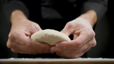 Aşçı hamuru düzleştirir. Mutfaktaki ahşap masanın üzerinde.