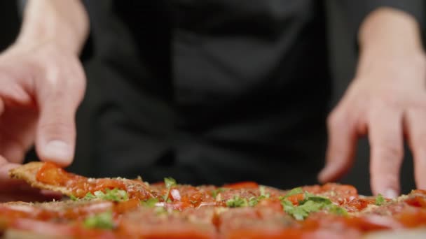 Man smakar vegansk pizza i det svarta köket — Stockvideo