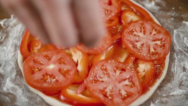 The chef sprinkles salt and spices for the pizza on a black background — Stock Video