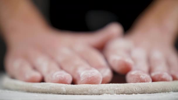 Cook prepares wheat dough for pizza on the black background — Stock Video