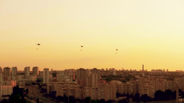 Groep gevechtshelikopters over de stad Mi-8 met vlaggen op rode warme zonsondergang — Stockvideo