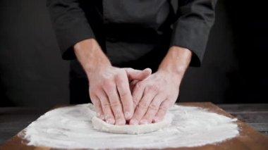Cook siyah arka plan üzerinde pizza için buğday hamuru hazırlar