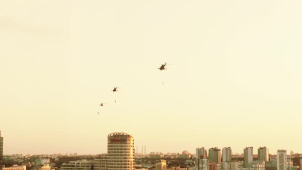 Groep gevechtshelikopters over de stad Mi-8 met vlaggen op rode warme zonsondergang — Stockvideo