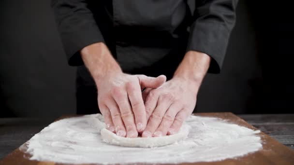 Повар готовит тесто пшеницы для пиццы на черном фоне — стоковое видео