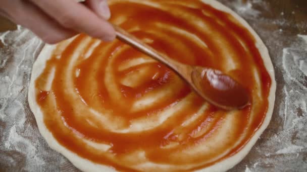 Salsa de tomate untada con cuchara de madera sobre masa de pizza — Vídeos de Stock