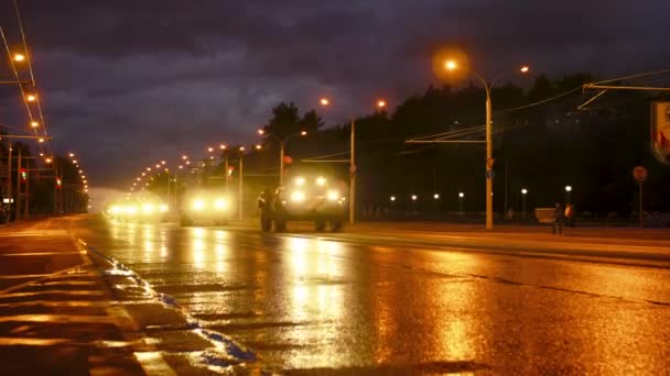 Konwój sprzętu wojskowego jeździ przez miasto nocą z reflektorami na — Wideo stockowe