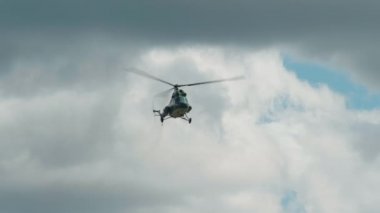 Helikopter yazın, güneşli bir günde bulutların arkasında uçar.