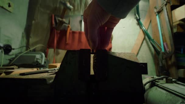 Adam, atölyede paslı mengeneye vida ile kavradı eski aletler tozla kaplı — Stok video