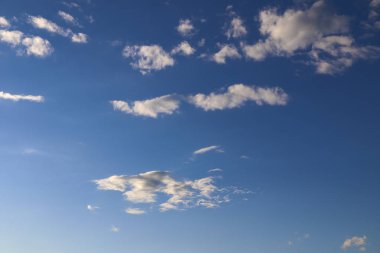mavi gökyüzü beyaz bulutlar ile akşam. Güneş bulutların arkasına gizler. gün batımında güneş ışınlarının kabarık bulutlar farklı renk aydınlatmak.