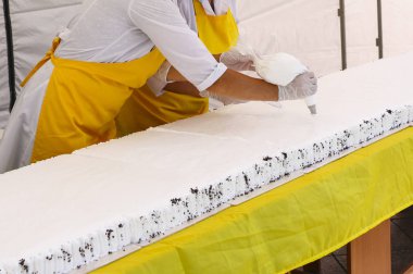 Tereyağı krema ile lezzetli kek dekorasyon pudra. Pudra büyük Festival kek pandispanya krem şanti beyaz krema koymak beyaz eldiven eller.