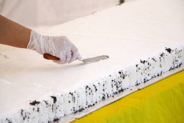 Tereyağı krema ile lezzetli kek dekorasyon pudra. Pudra büyük Festival kek pandispanya krem şanti beyaz krema koymak beyaz eldiven eller.