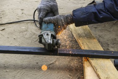İşçi eldiven eller metal boru taşlama tezgahı ile kesti. turuncu sinek Bileme Makinası kesme demir süre gelen kıvılcımlar.