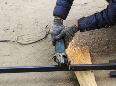 İşçi eldiven eller metal boru taşlama tezgahı ile kesti. turuncu sinek Bileme Makinası kesme demir süre gelen kıvılcımlar.