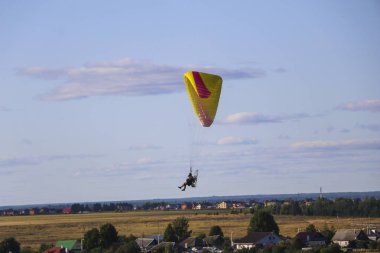 Motor paraplan uçuşu. parlak renkli motoparaplane Köyü, alan ve inşaat site yukarıda adam uçar.
