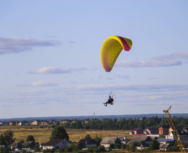 Motor paraplan uçuşu. parlak renkli motoparaplane Köyü, alan ve inşaat site yukarıda adam uçar.