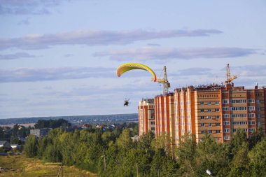 Motor paraplan uçuşu. parlak renkli motoparaplane Köyü, alan ve inşaat site yukarıda adam uçar.